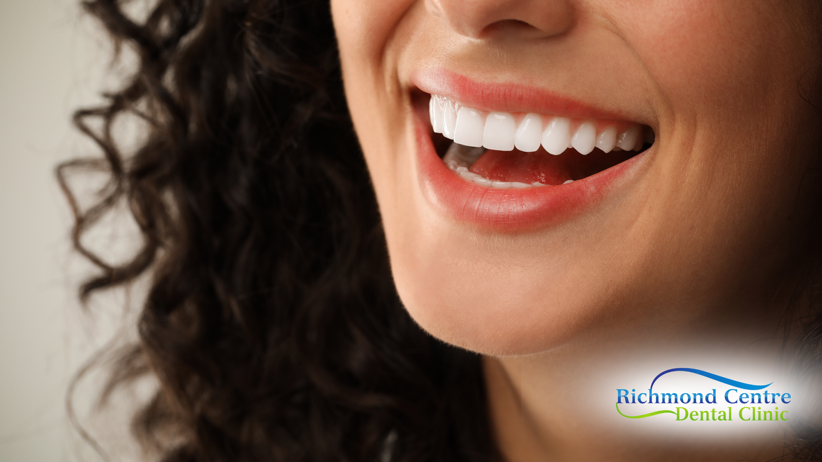 A close up of a woman 's smile with a richmond center dental clinic logo in the background