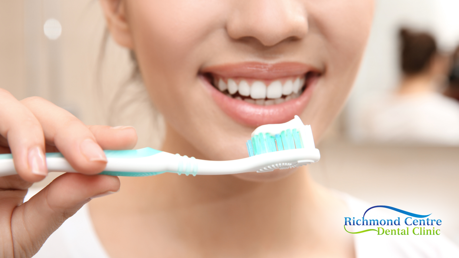 Woman holding toothbrush with toothpaste, smiling in bathroom.